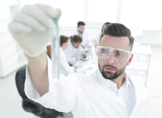 image is blurred. young scientist holding tube with the reagents