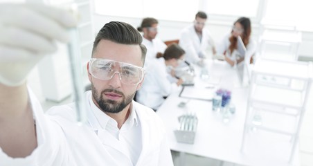 image is blurred. young scientist holding tube with the reagents