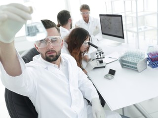 biochemist with flask Petri sitting at a Desk