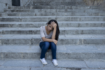 Fototapeta na wymiar beautiful and sad Hispanic woman desperate and depressed sitting on urban city street staircase