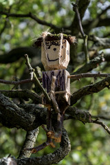 Wooden figurine sitting on branches.