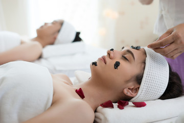 Obraz na płótnie Canvas Beautiful woman getting facial black mud mask at beauty salon.