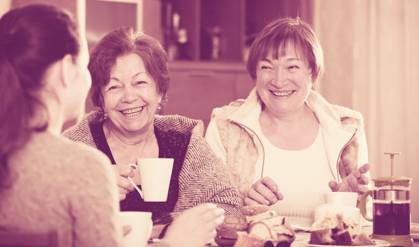 Senior women talking with girl while tea drinking