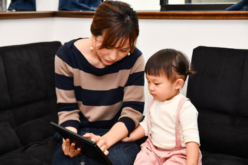 タブレットを操作する日本の幼児と若く美しい母親
