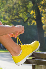 Tying running shoes on a bench in the park.