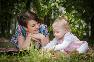 Mother and daughter have fun in the park and apple tree with white flowers