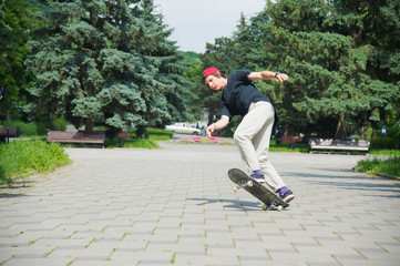 Long-haired skater-teenager in a T-shirt and a sneaker hat jumps an alley against a stormy sky