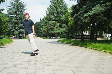 Fototapeta premium Long-haired skater-teenager in a T-shirt and a sneaker hat jumps an alley against a stormy sky