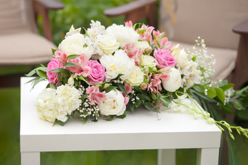 Flower arrangement with pink and white roses, wedding day, outdoors.