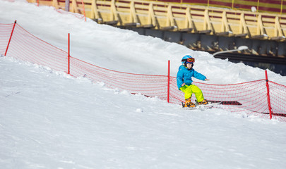 Little boy falling down while skiing in children's area