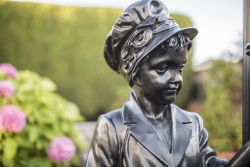 Black metal or bronze garden statue of a Victorian girl wearing a bonnet