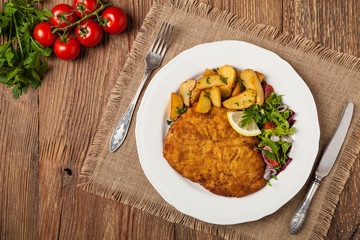 Chicken schnitzel, served with roasted potatoes and salad.