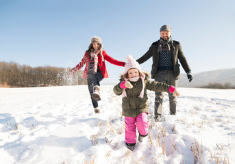 Father and mother with their daughter, playing in the snow.