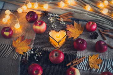 autumn composition of apples, a candle, the lights, the garland, the falling leaves, a warm blanket