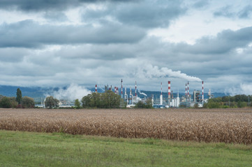 Fototapeta na wymiar panorama usine chimique en plain champ sur fond de ciel nuageux