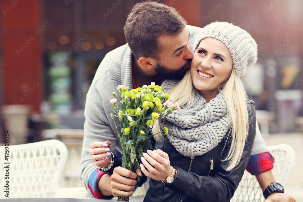 Wall mural Picture showing young couple with flowers dating in the city