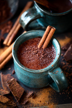 Cup of hot chocolate with a stick of cinnamon and the flakes of grated dark chocolate