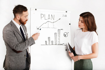 Man and woman dressed in office style debate about graph on white board