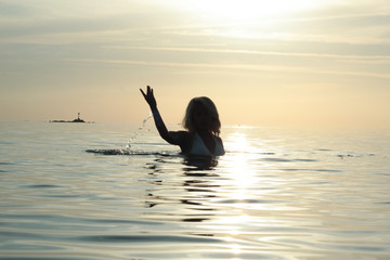silhouette woman in the sea playing under the sunset in the peaceful island