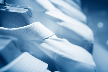 Fototapeta premium Męskie swetry i koszule w różnych kolorach na wieszakach w sklepie z odzieżą
