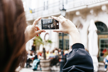 Woman takes a photo of city square on her smartphone