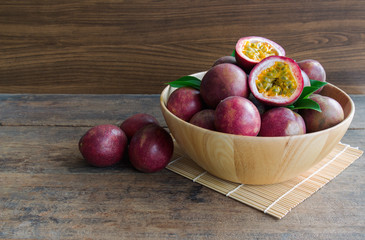Fresh passion fruit in wood bowl on wood table in side view with copy space for background or wallpaper. Ripe passion fruit so delicious sweet and sour. Tropical fruit.