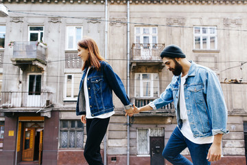 Woman holds man's hand walking with him on the city