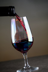 Pouring red wine into the glass against rustic background