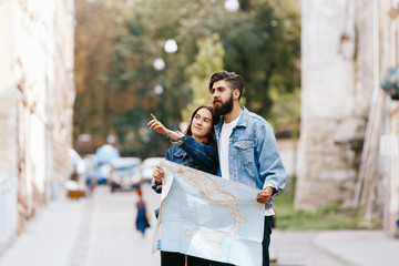 Woman shows something to her bearded man standing together with touristic map