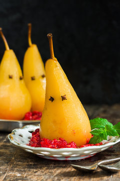 Pears poached in sweet syrup on crushed raspberries, presented as ghosts. Halloween food idea.