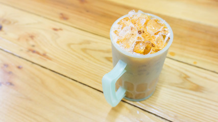 Iced tea with milk on wooden background