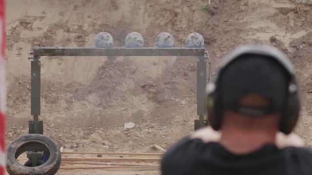 FullHD footage. Man in headphones shoots a pistol on the target plates.