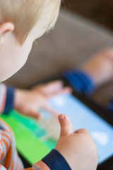 Child using a touch screen tablet to play learning game