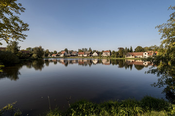 reflections of small village houses in pond water on the village square