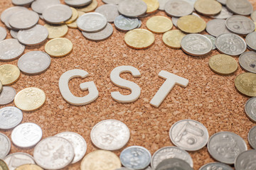 The word GST (Goods and services tax) with coins over wooden  background