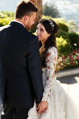 Look from behind at beautiful wedding couple walking in Naples