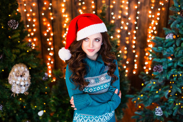 Beautiful brunette woman in red santa hat and sweater at home.