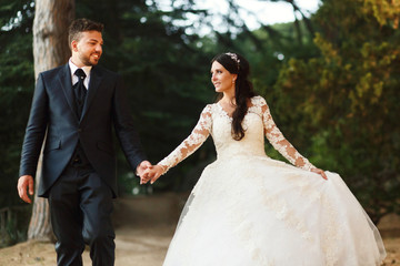 Handsome groom and pretty bride walk in the green park