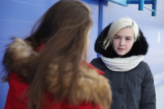 Young beautiful girl on a walk in winter at blue wall