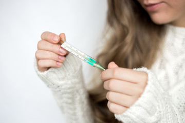  attractive girl in a white sweater with a thermometer sick