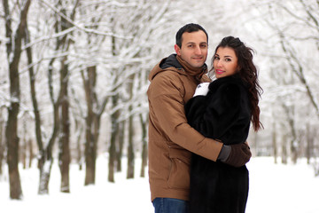 A young couple walk in a winter park