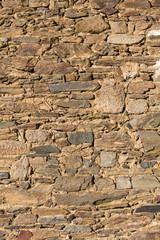 Side view of the sunlit stone patterns on an old dry stone wall.