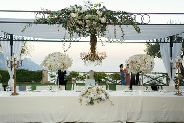 Chandelier with flowers and greenery hangs over dinner table for newlyweds