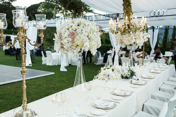 Chandelier with flowers and greenery hangs over dinner table for newlyweds