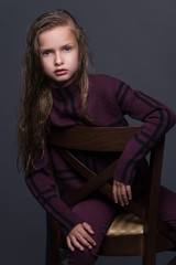 Portrait of cute little girl with dark hair in studio over grey background.