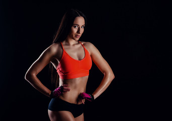 Fototapeta na wymiar Nice sexy fitness woman showing abdominal muscles isolated over black background. Trained female body.
