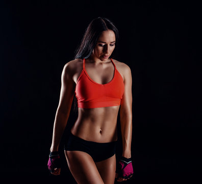 Nice sexy fitness woman showing abdominal muscles isolated over black background. Trained female body.