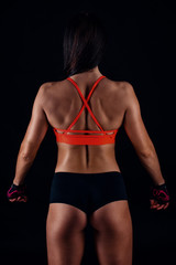 Beautiful fitness sexy slim female in activewear posing over black background. Back view.