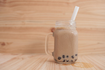 Jar glass Ice milk tea and bubble , Ice milk tea on the wood floor and wood background 