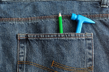 A toy plastic hammer in a back pocket of a denim with a pencil